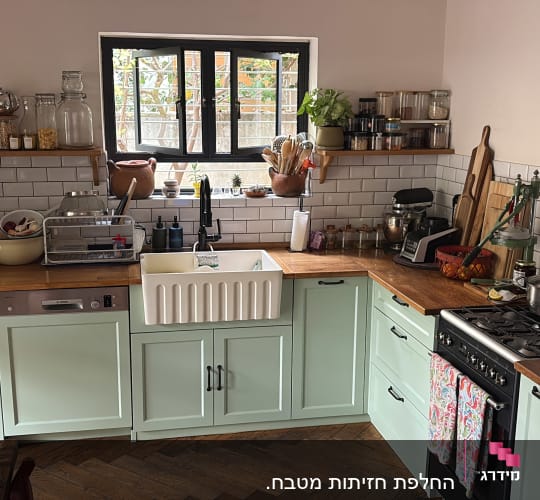 מטבח עם ארונות ירוקים וכלי מטבח שונים